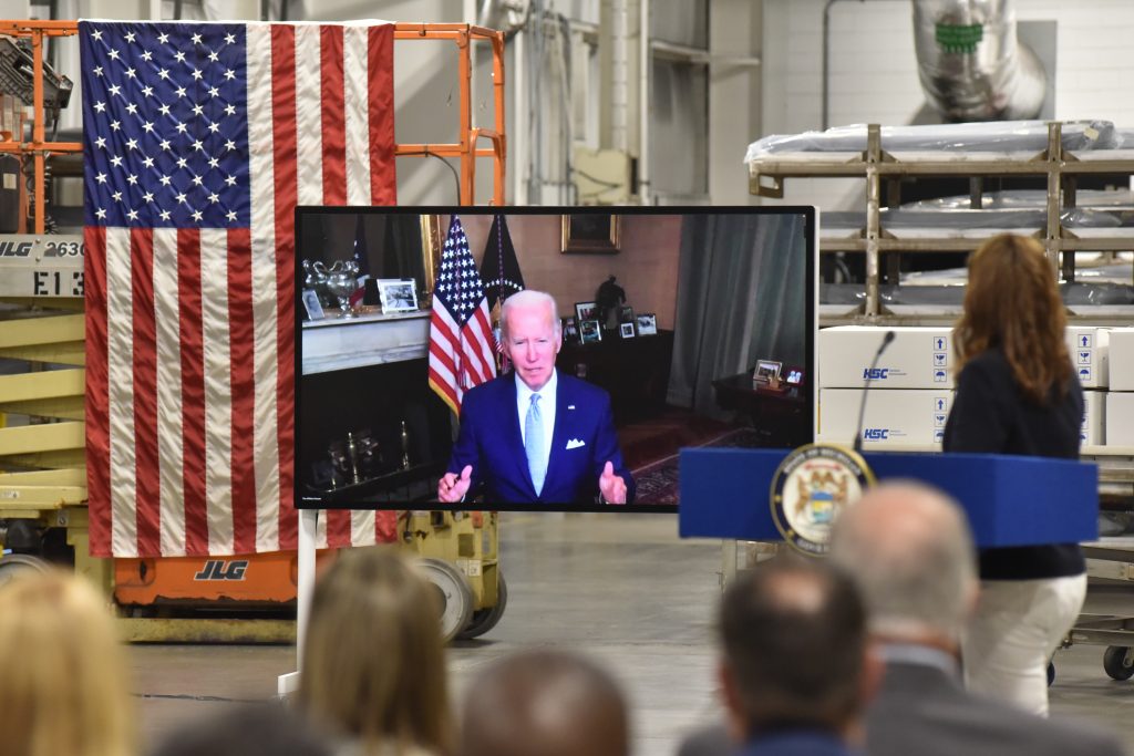 President Biden on a TV screen with audience looking at him