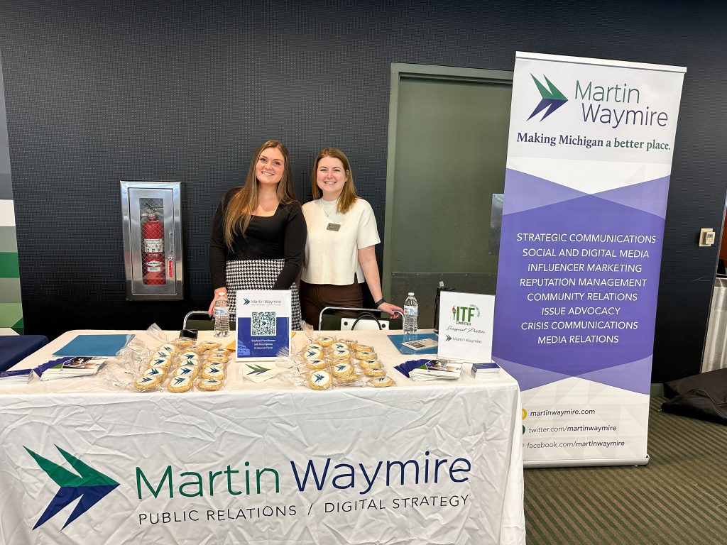 Megan Stefl and Hannah Lupi at MSU career fair standing with table of Martin Waymire swag