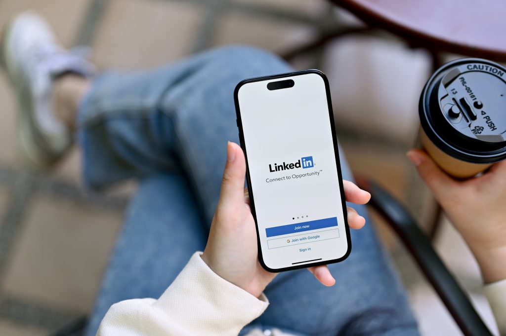 Person holding an iphone with linkedin login page up on the phone screen.