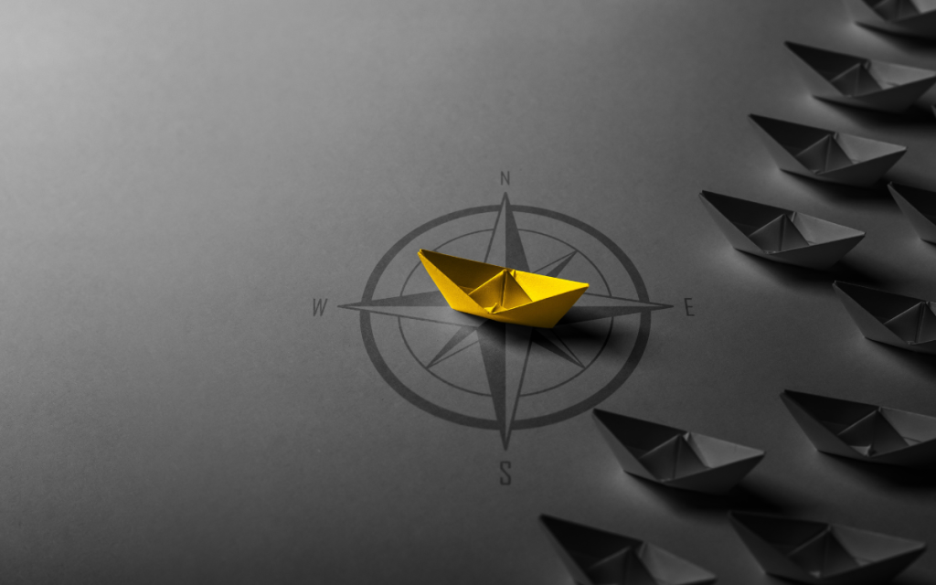 yellow paper boat over a compass, leading other boats